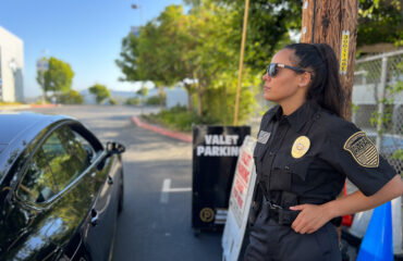 Licensed security guard with guard card on duty near a parking area, monitoring surroundings and assisting with site security operations