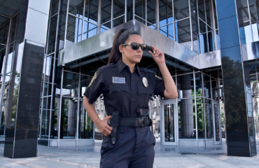 Professional security guard standing outside a modern commercial building in California, representing armed security services for high-risk properties and business protection.