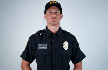 Professional hotel security guard standing alert in uniform with a communication earpiece, representing proactive hotel security measures, guest safety, and liability risk management in 2026.